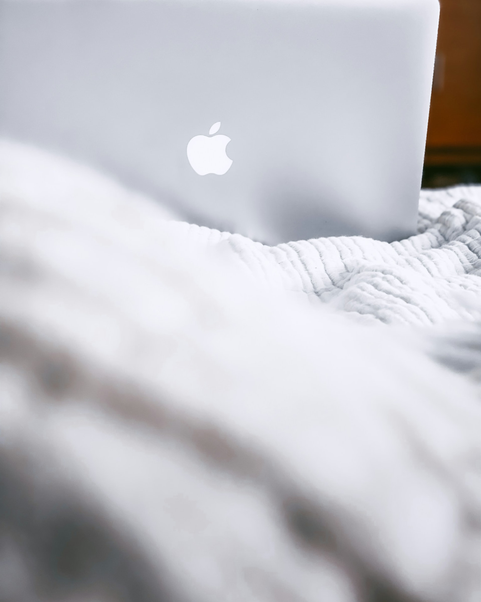 A laptop open on a white bed